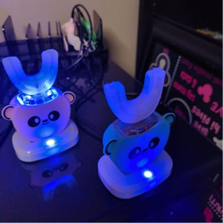 Two Sonic Brush Kids toothbrushes glowing on a bathroom counter at night